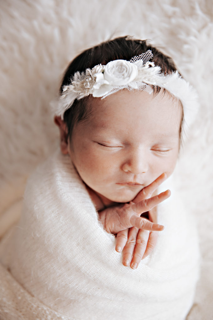 Nouveau-né avec bandeau fleuri en gros plan, photo naissance studio Provence