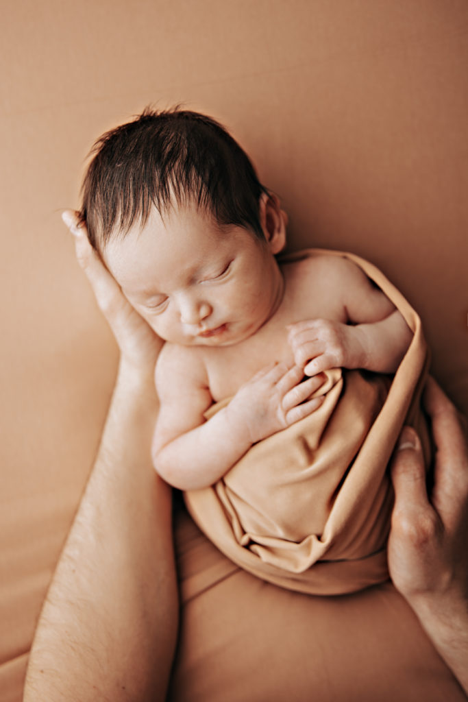 Nouveau-né endormi dans les mains des parents, photo naissance studio Provence