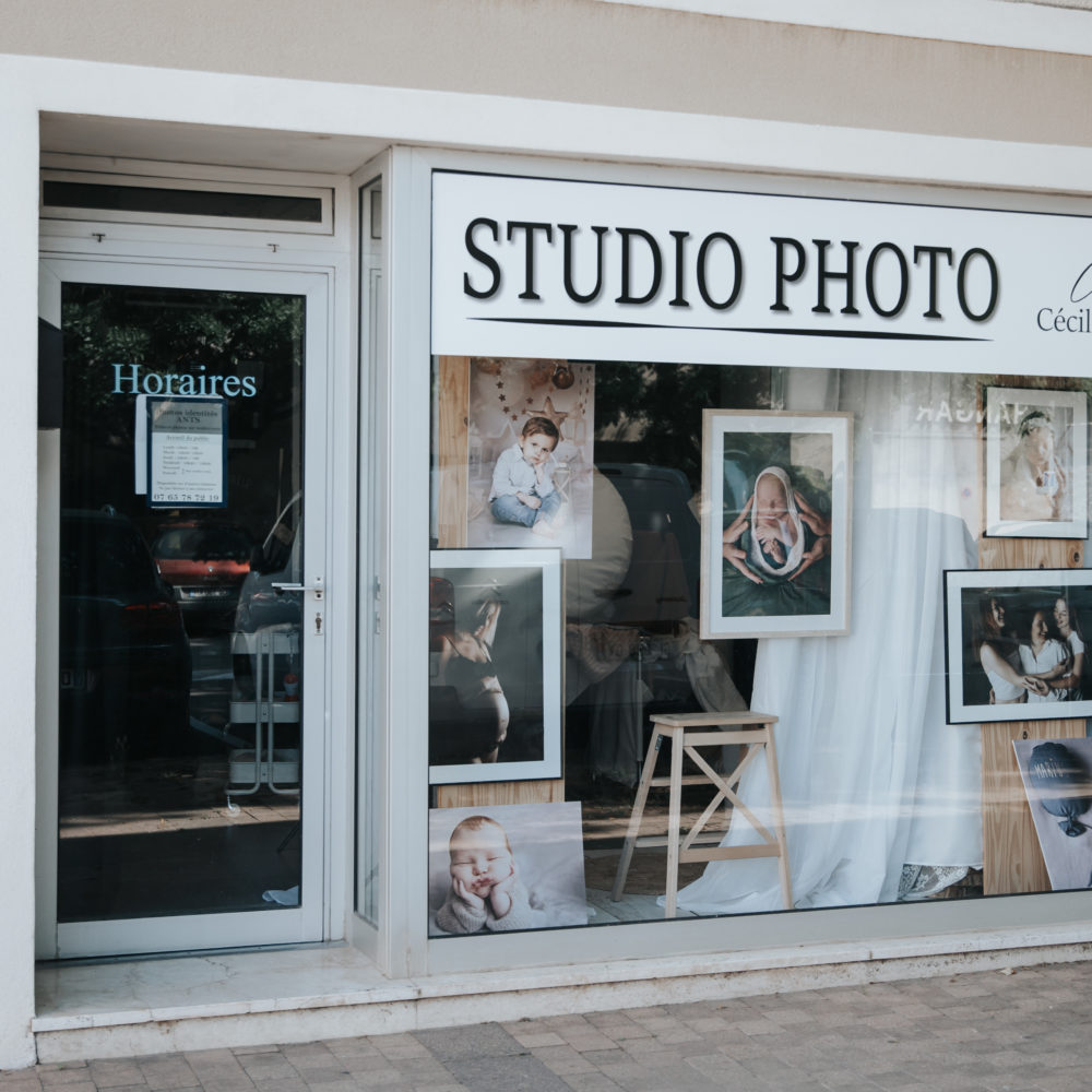 Façade du studio photo de Cécile Muselet à Aramon, avec vitrine décorée de portraits de famille, de bébés et de femmes enceintes