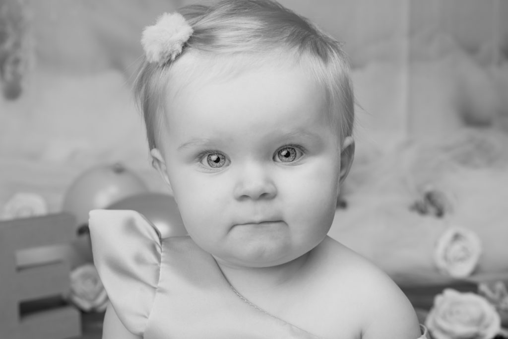 Portrait d’un bébé en tenue d’anniversaire, regard profond et expression sérieuse