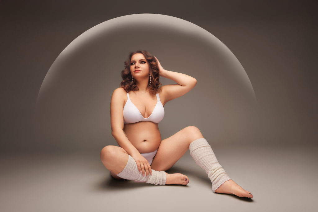 Femme enceinte assise en sous-vêtements blancs dans un univers doux et moderne
