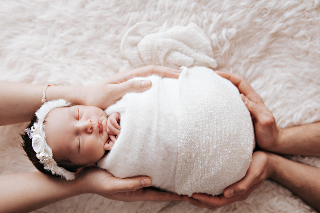 Nouveau-né emmailloté allongé sur fond clair, photo bébé studio Provence