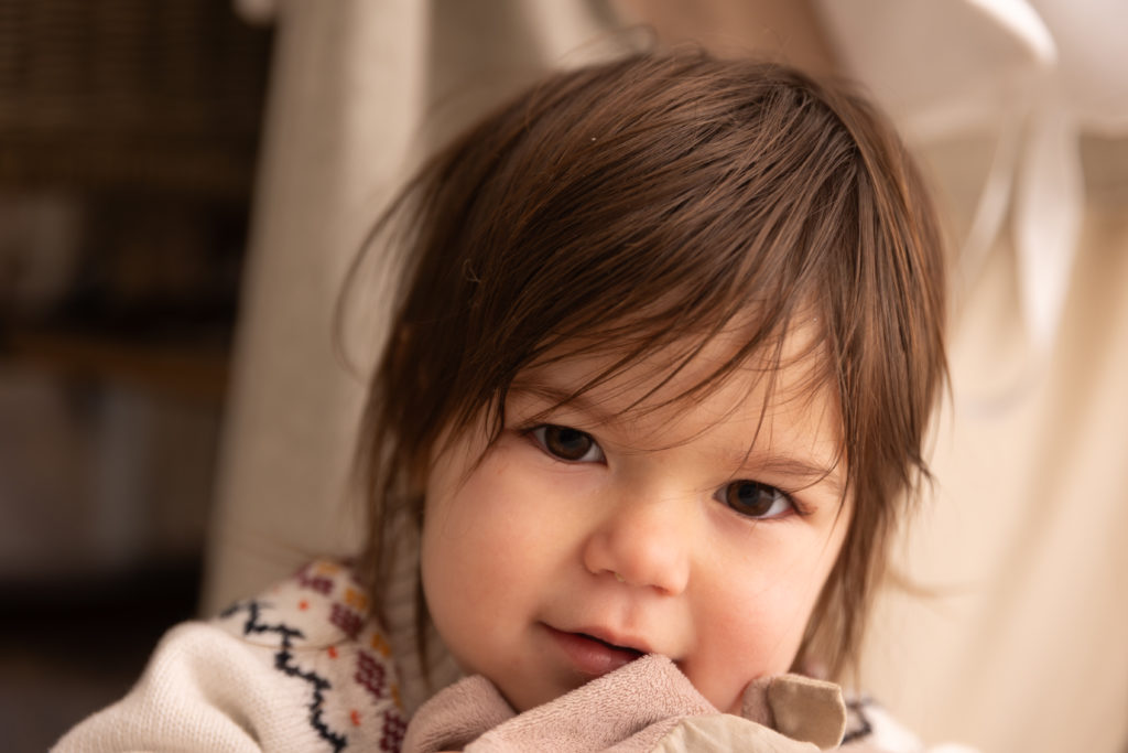 Portrait d’une petite fille avec son doudou, regard doux et tendre vers l’objectif