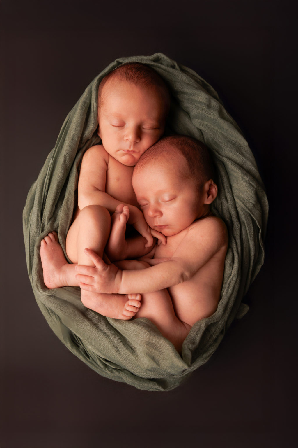 Deux nouveau-nés jumeaux dormant paisiblement, lovés dans un tissu vert