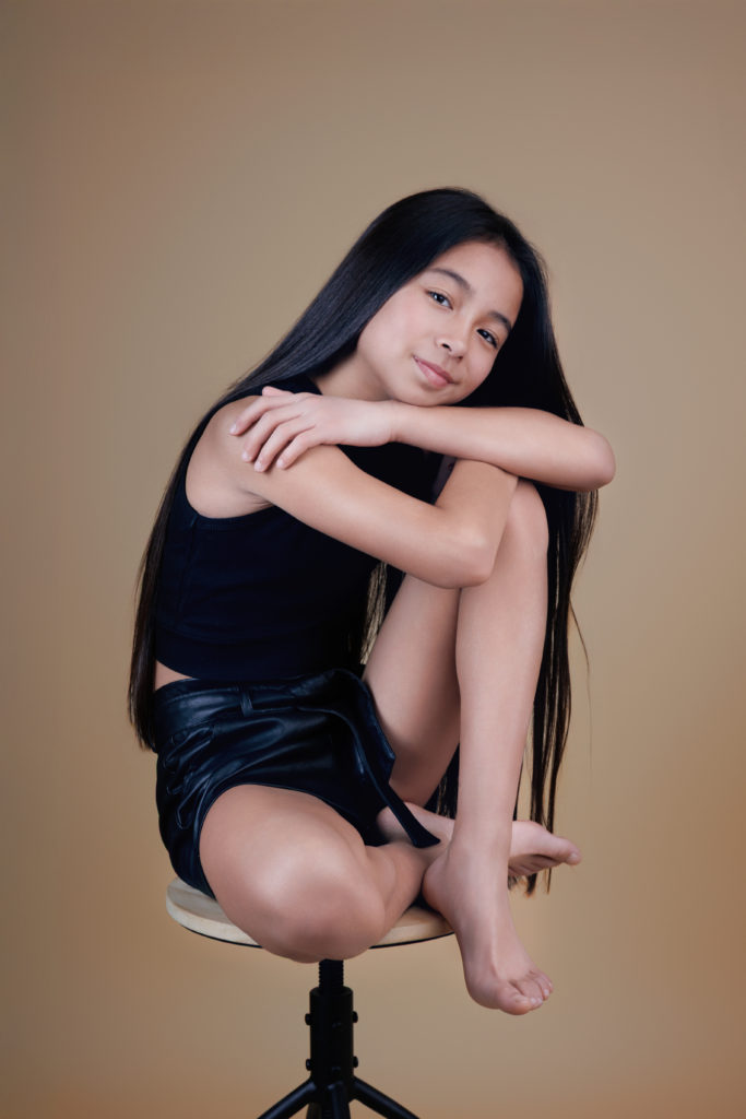 Jeune fille assise sur un tabouret, posant avec douceur et confiance