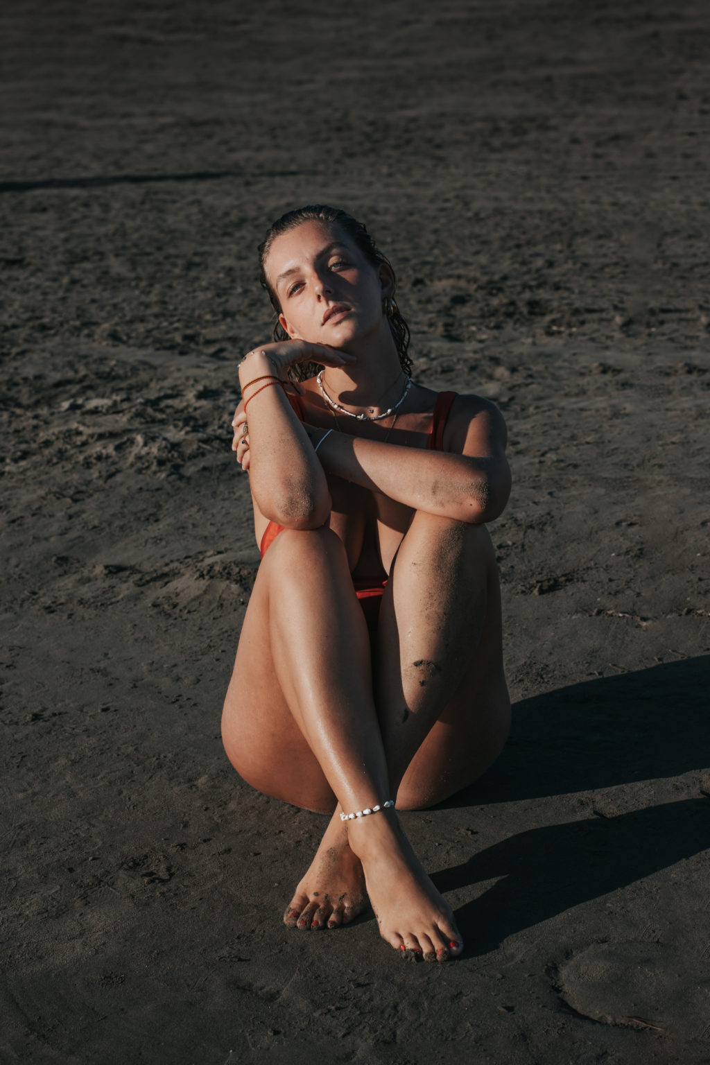 Femme assise sur le sable, regard profond, fin de journée