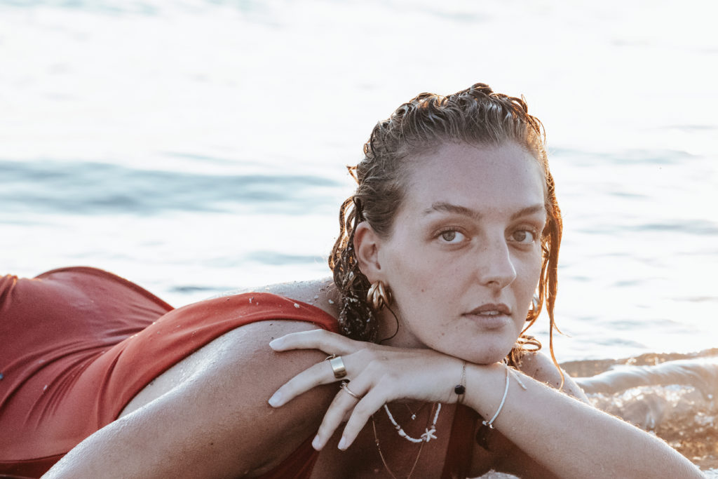 Femme au regard intense, allongée dans l’eau au bord de la mer