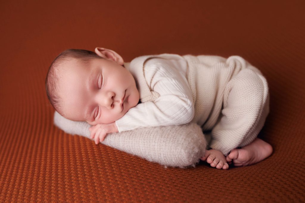 Nouveau-né endormi allongé sur coussin clair, photo bébé studio Provence