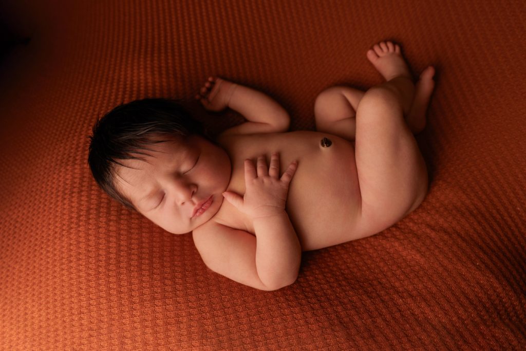 Nouveau-né endormi sur fond terracotta, photo naissance studio Provence