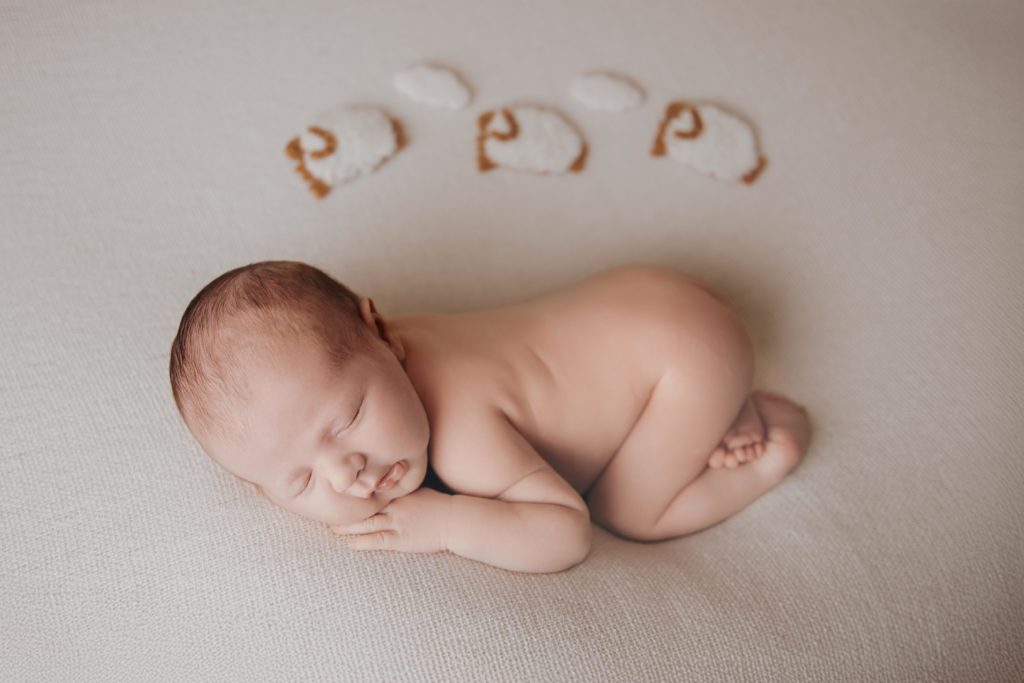 Nouveau-né endormi sur fond clair avec accessoires, photo naissance en studio à Rognonas près d’Avignon