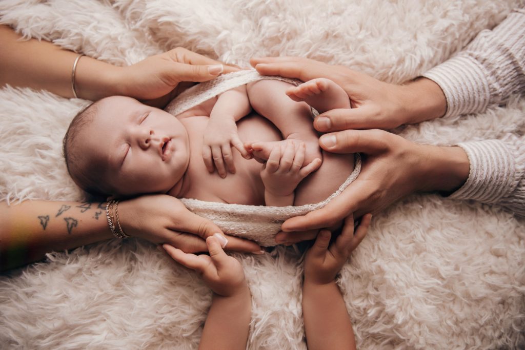 Frère et sœur entourant un nouveau-né allongé, photo famille naissance studio Provence